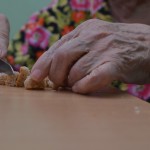 Бабушка режет хлеб на мелкие кусочки. Так для нее удобнее