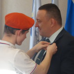 Капитан юных пожарных цепляет значок дружины Клопову